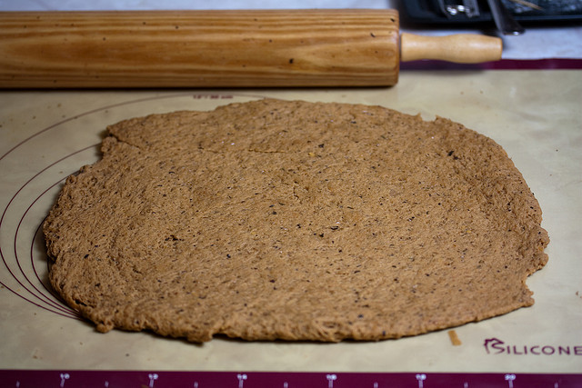 Masa de seitan extendida sobre una superficie de silicona con un rodillo de madera al fondo.